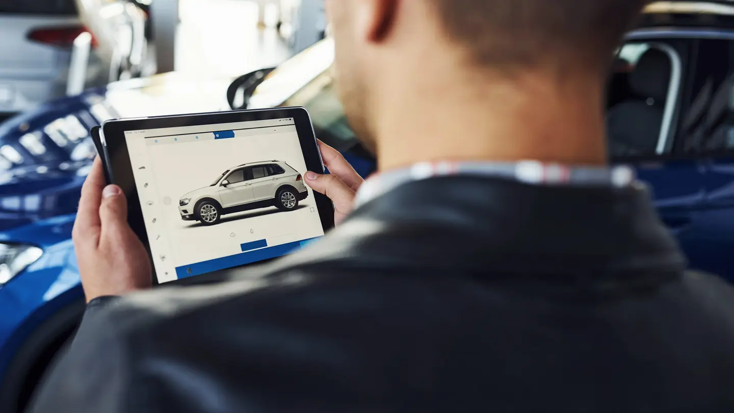 Autoankäufer bewertet Fahrzeug am Tablet